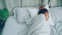 A young woman sleeping peacefully in a white bed